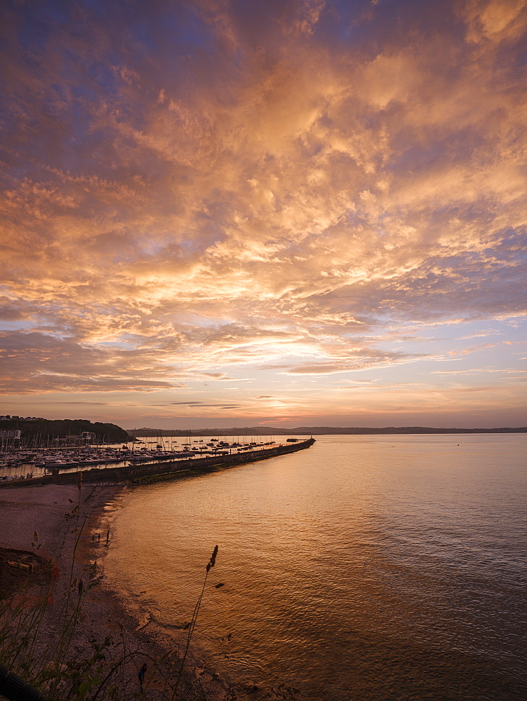 Colourful sunset view of Breakwater Beach and the harbour wall of Brixham, Devon, England, United Kingdom, Europe