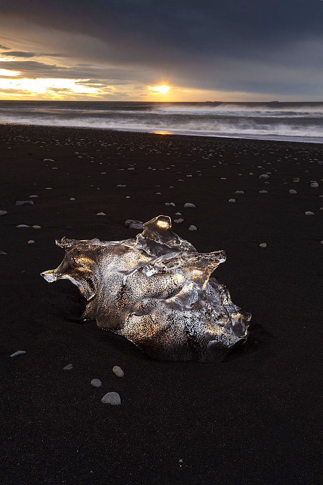 Glacier ice on black sand beach backlit with the sun, near Jokulsarlon, South Iceland, Iceland, Polar Regions