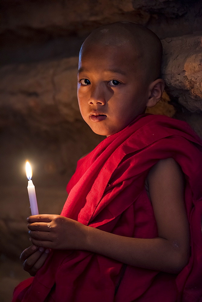 A young Buddhist monk holding candle at temple, Bagan (Pagan), Myanmar (Burma), Asia