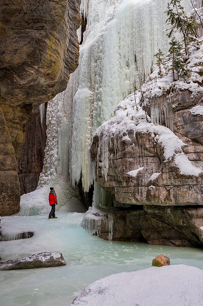 A man wearing red coat stood in Maligne Canyon during winter conditions, Jasper National Park, UNESCO World Heritage Site, Alberta, Canada, North America