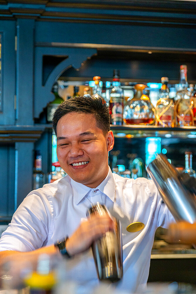 Bar tender with cocktail shakers making Singapore slings, Long Bar, Raffles Hotel, Singapore, Southeast Asia, Asia