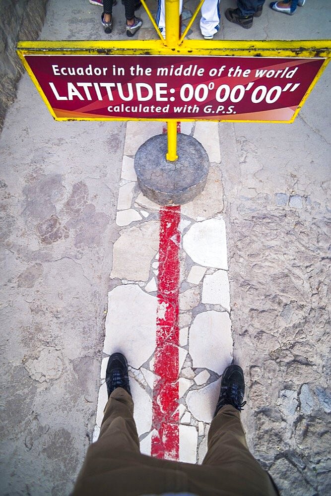 One foot in the northern and southern hemisphere at the Equator at 'Middle of the World', San Antonio de Pichincha, Quito, Ecuador, South America