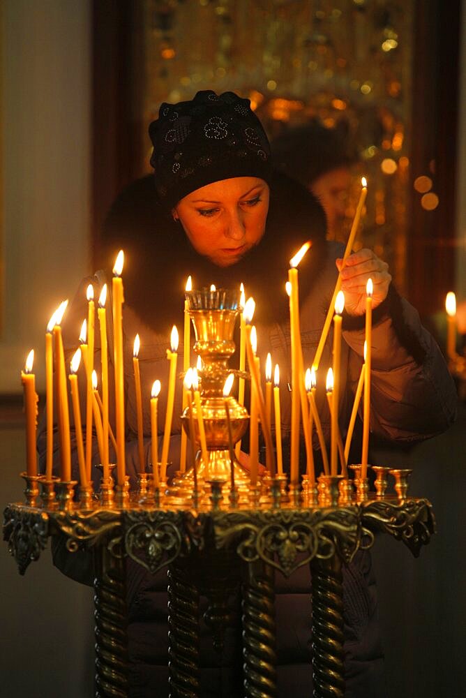 Trinity Cathedral. Woman lighting a candle .