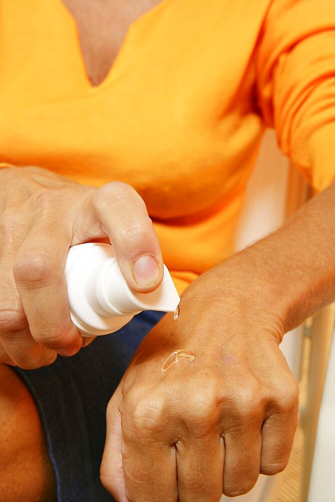 Mature woman putting hormone gel on hand as part of hormone replacement therapy