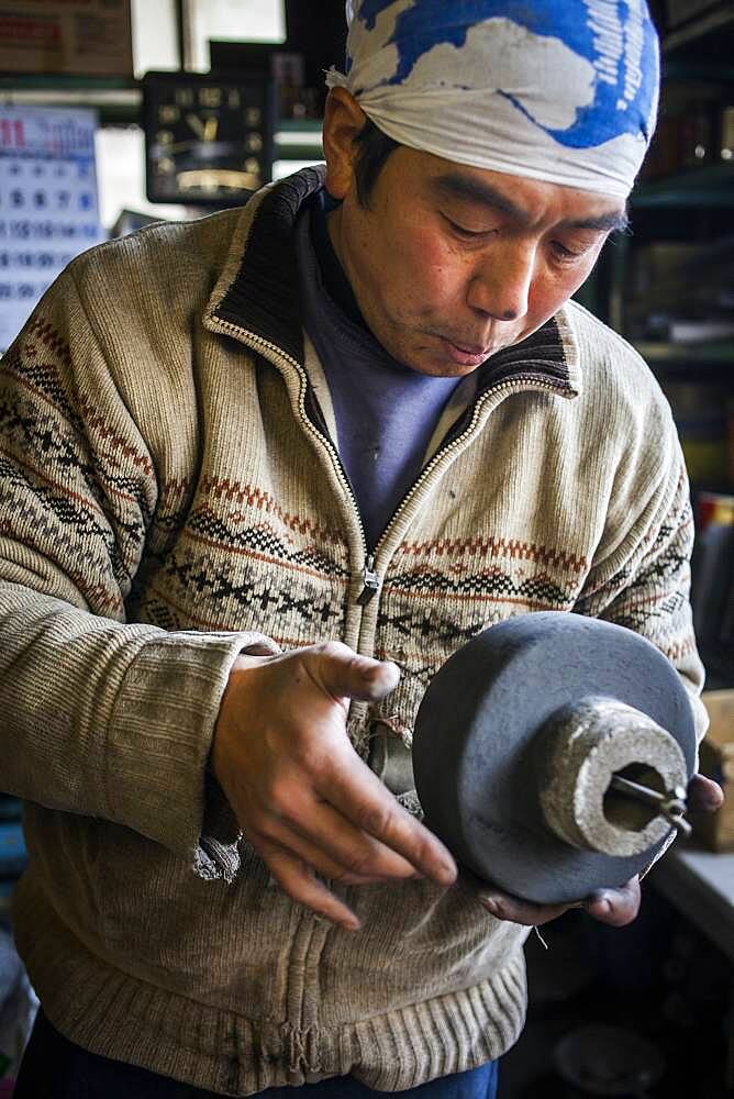 Takahiro Koizumi is preparing the inner mold, to make a iron teapot or tetsubin, nanbu tekki,Workshop of Koizumi family,craftsmen since 1659, Morioka, Iwate Prefecture, Japan