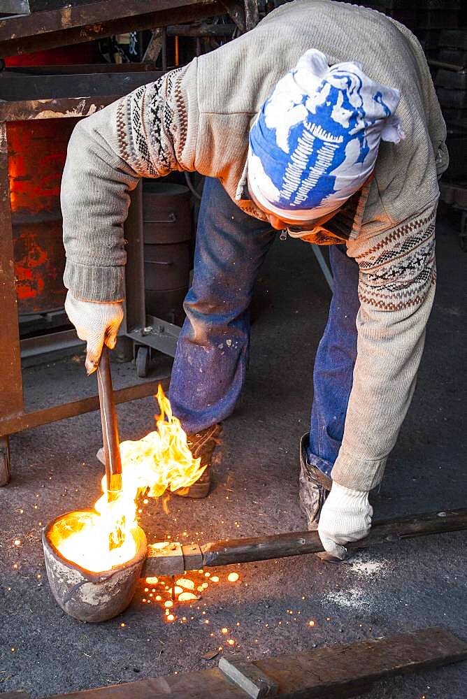 Waiting for the right temperature. Takahiro Koizumi carries molten iron with spoon to pour it into the mold, to make a iron teapot or tetsubin, nanbu tekki,Workshop of Koizumi family,craftsmen since 1659, Morioka, Iwate Prefecture, Japan