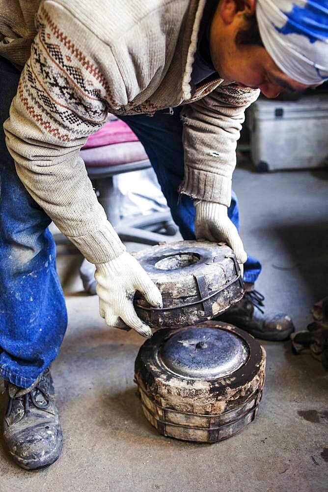 Takahiro Koizumi is opening the mold Just  after solidifying the molten iron. He casts the first look at new iron teapot or tetsubin, nanbu tekki, Workshop of Koizumi family,craftsmen since 1659, Morioka, Iwate Prefecture, Japan