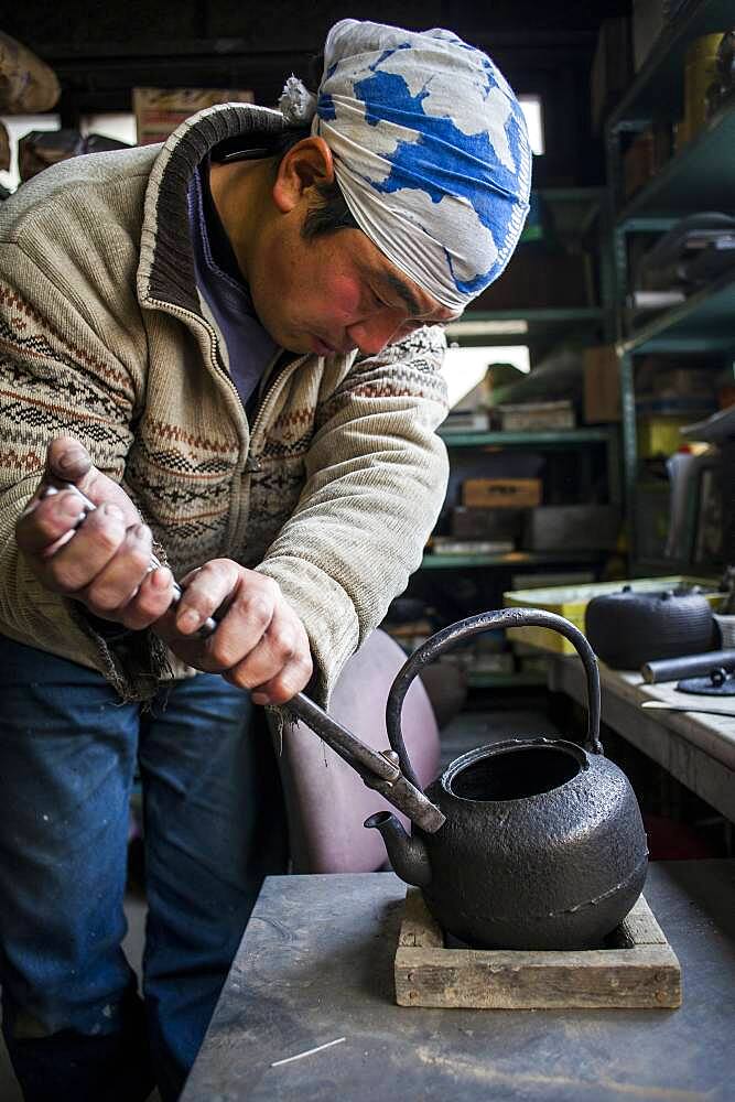 Takahiro Koizumiis putting the handle at iron teapot or tetsubin, nanbu tekki, Workshop of Koizumi family,craftsmen since 1659, Morioka, Iwate Prefecture, Japan