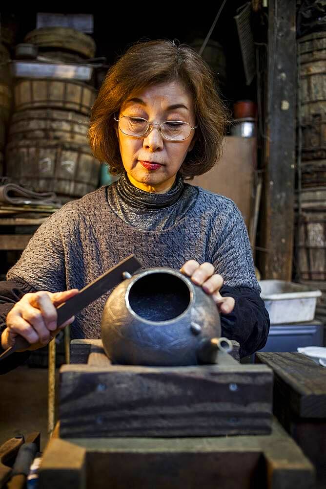 Morihisa Suzuki  is putting the finishing touches at iron teapot or tetsubin, the only woman who has made teapots in the nearly 400 years of history that has molten iron crafts in Iwate, in Workshop of Morihisha Suzuki,craftsmen since 1625, nanbu tekki, Morioka, Iwate Prefecture, Japan