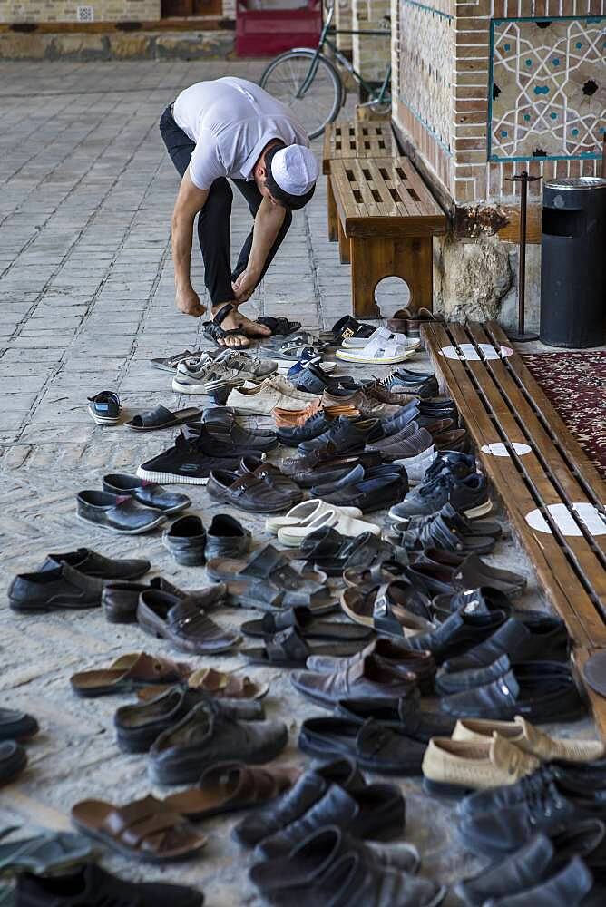 Believer takes off his shoes, in Bolo Hauz Mosque, Bukhara, Uzbekistan