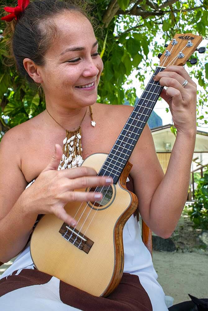 Beautiful local woman playing ukulele next to Bora Bora Vaitape dock, Society Islands, French Polynesia, South Pacific.