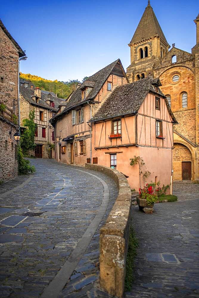 The small medieval village of Conques in France. It shows visitors its abbey-church and clustered houses topped by slate roofs.  Crossing of narrow streets and monolith to the fallen ones in the war in the old medieval village of Conques on coats of the river Dordou