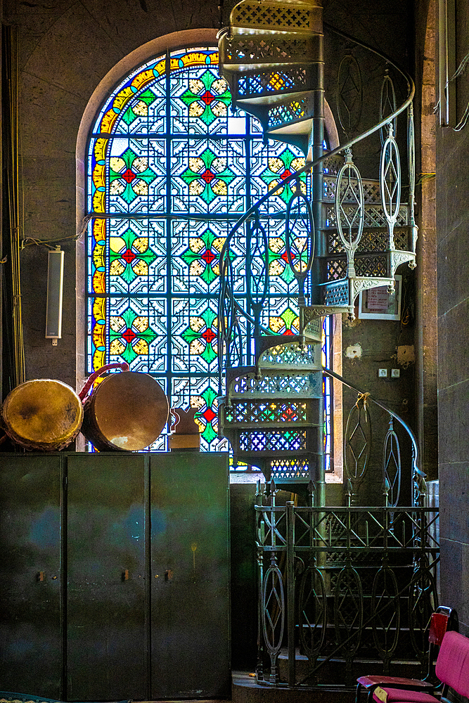 A spiraling metal staircase in front of a stained glass window, Addis Ababa, Ethiopia