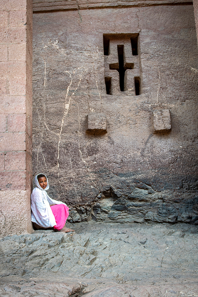 A young girl sitting against the walls of Bet Medhane Alem (Church of the World Savior) in Lalibela, Ethiopia