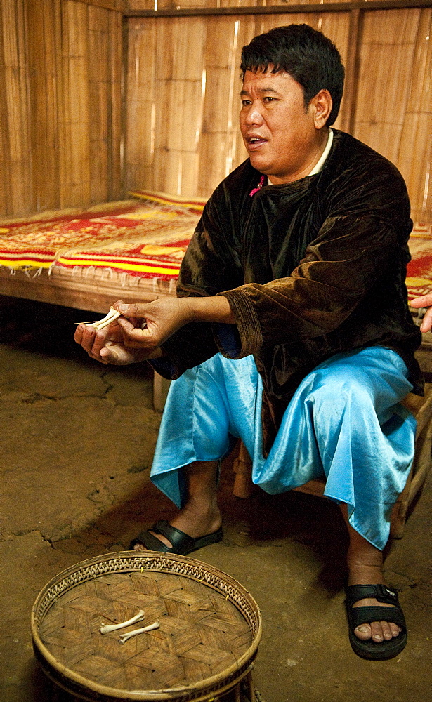 Local shaman explaining how he interprets chicken bones that people bring to him for guidance, in the Lisu village of Sridongyen in rural Chiang Mai Province, Thailand.