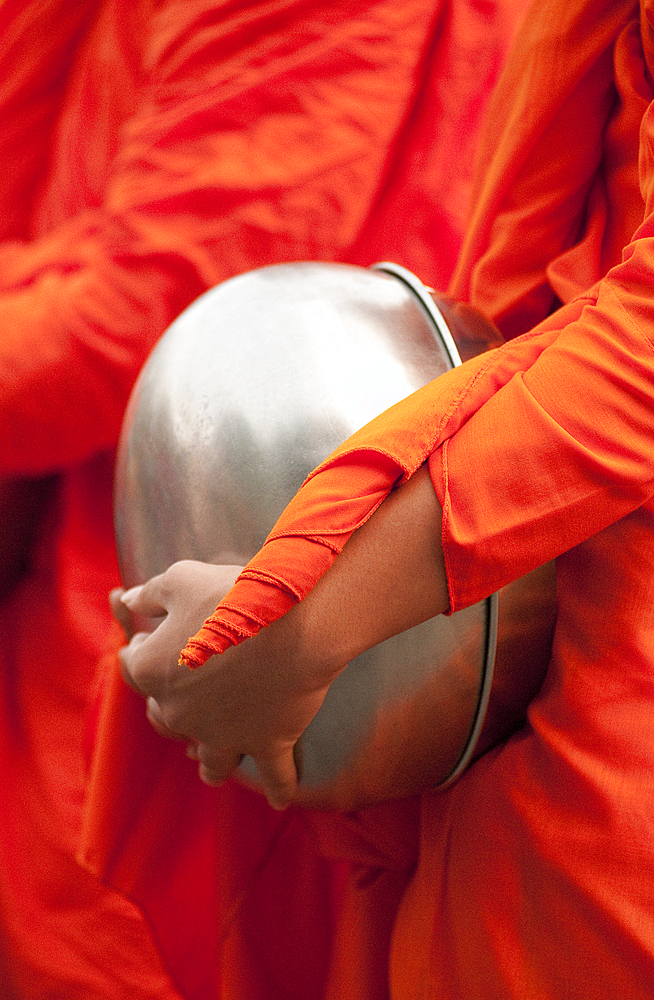 Buddhist monk with bowl during morning procession for offerings of food; Huay Kaew area, Chiang Mai, Thailand.