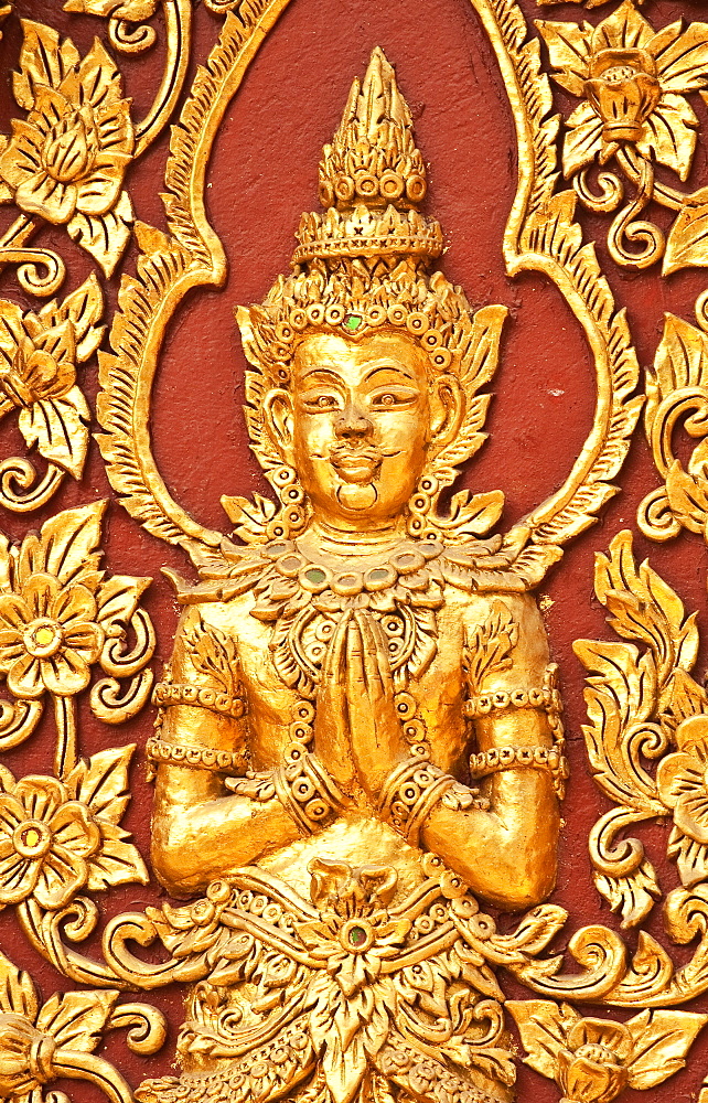 Golden Buddha figure detail on wall of Wat Mahawan Buddhist temple in Chiang Mai, Thailand.