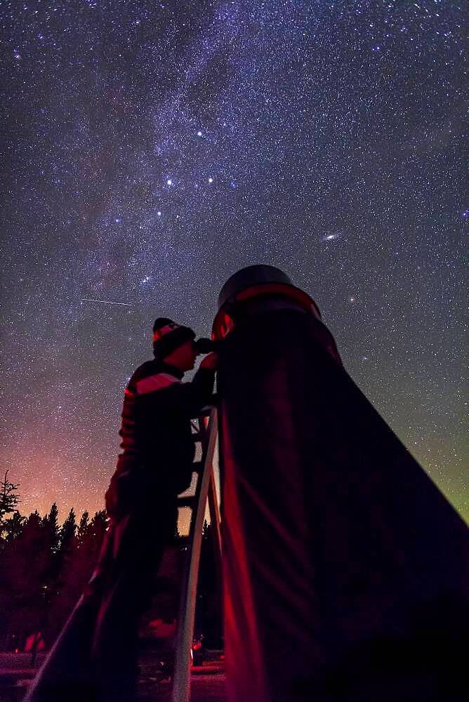 Astronomer Vance Petriew at the eyepiece of his 20-inch Dobsonian reflector telescope, at the 2012 Saskatchewan Summer Star Party in Cypress Hills, SK. This is a single 20 second exposure with the Canon 5DMkII at ISO 4000, and 24mm Canon L-series lens at f/2. A faint aurora adds the horizon colours. The photo was taken on the occasion of the second return of Comet Petriew 185/P since its discovery 11 years earlier in 2001 at this very same location.