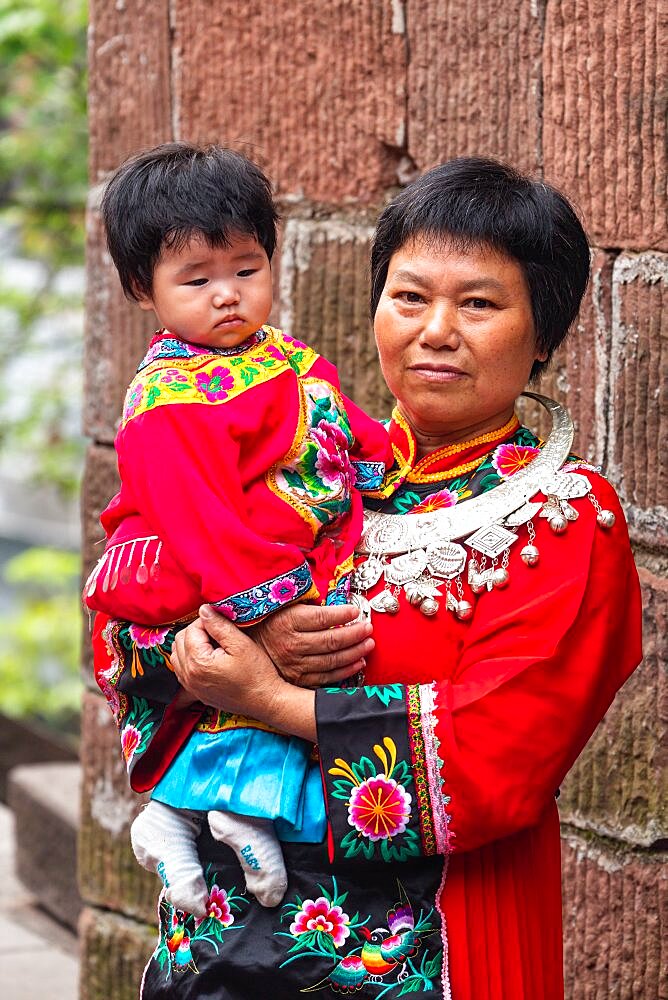 A mother and child pose in the traditional ceremonial dress of the Miao ethnic minority in Fenghuang, China.