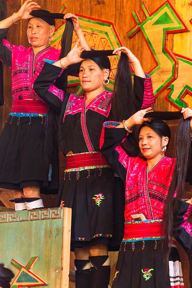 Red Yao ethnic minority woman demonstrate how they fix their traditional long hair. Huangluo, China.