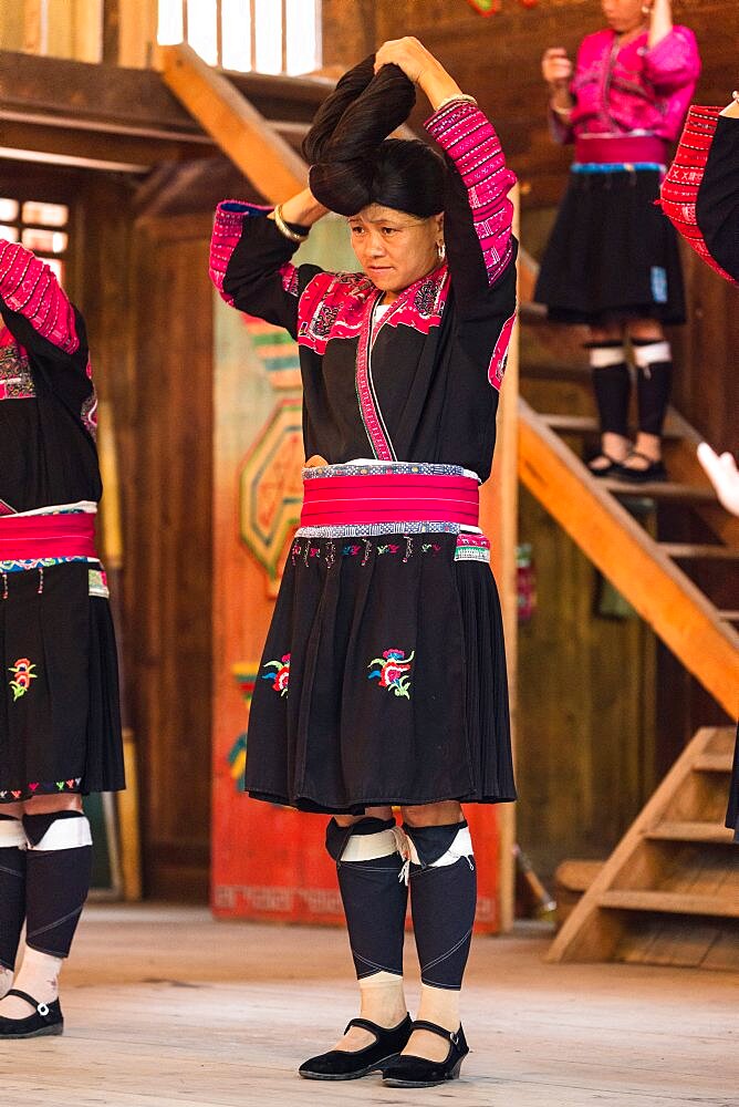 Red Yao ethnic minority woman demonstrate how they fix their traditional long hair. Huangluo, China.