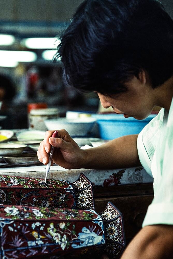 An artisan applies enamel frit with an eyedropper on a cloissone vase in a workshop in Beijing, China.