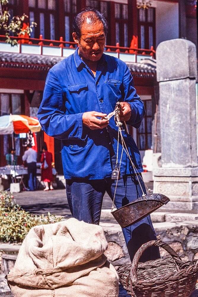 A vendor in the farmers market counts his money. Mutianyu, China.