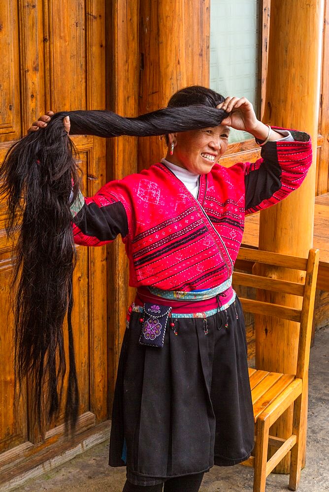 A woman of the Red Yao ethnic minority fixes her traditional long hair. Jinkeng, Longshen, China.