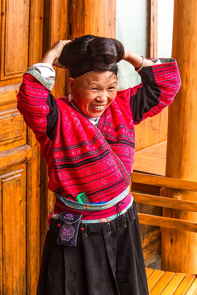 A woman of the Red Yao ethnic minority fixes her traditional long hair. Jinkeng, Longshen, China.