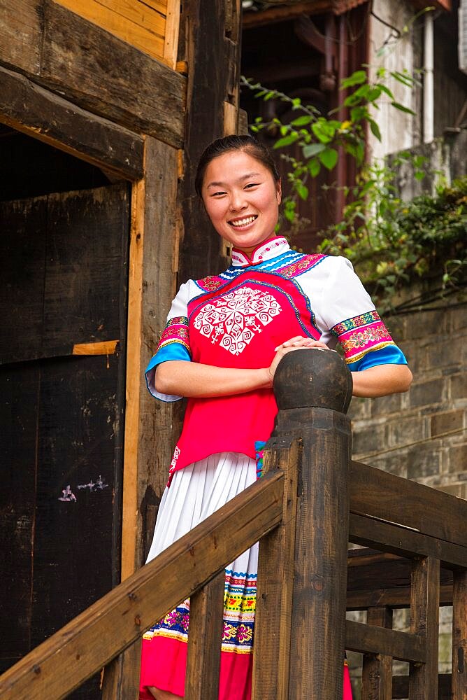 An attractive young woman in traditional ethnic Tujia dress poses for a portrait in Furong, China.