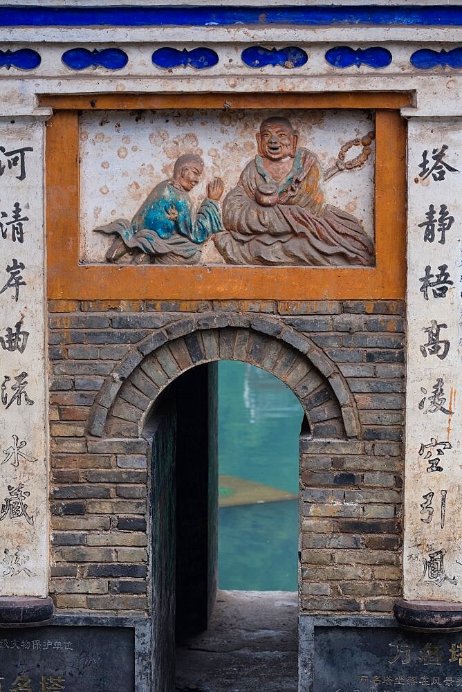 A bas relief frieze of Buddha over a small gate through the city wall of the Fenghuang Ancient Town, China.