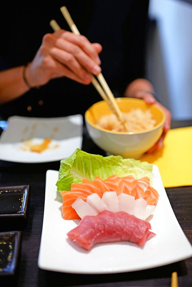 Woman eating white rice with sashimi