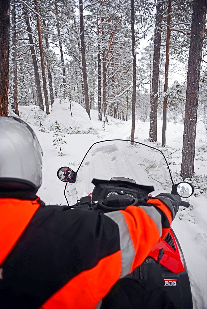 Antti, young Finnish guide from VisitInari, rides a snowmobile in the wilderness of Inari, Lapland, Finland