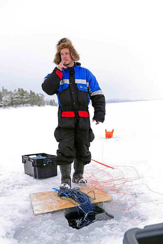 Fisherman practicing ice fishing in Lake Inari, Lapland, Finland