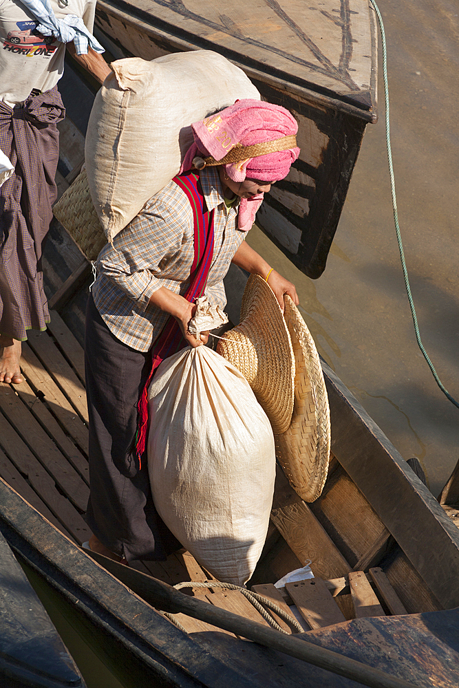 Woman carrying sacks off a boat, Inle Lake, near Indein and Nyaung Ohak villages, Shan State, Myanmar, (Burma)