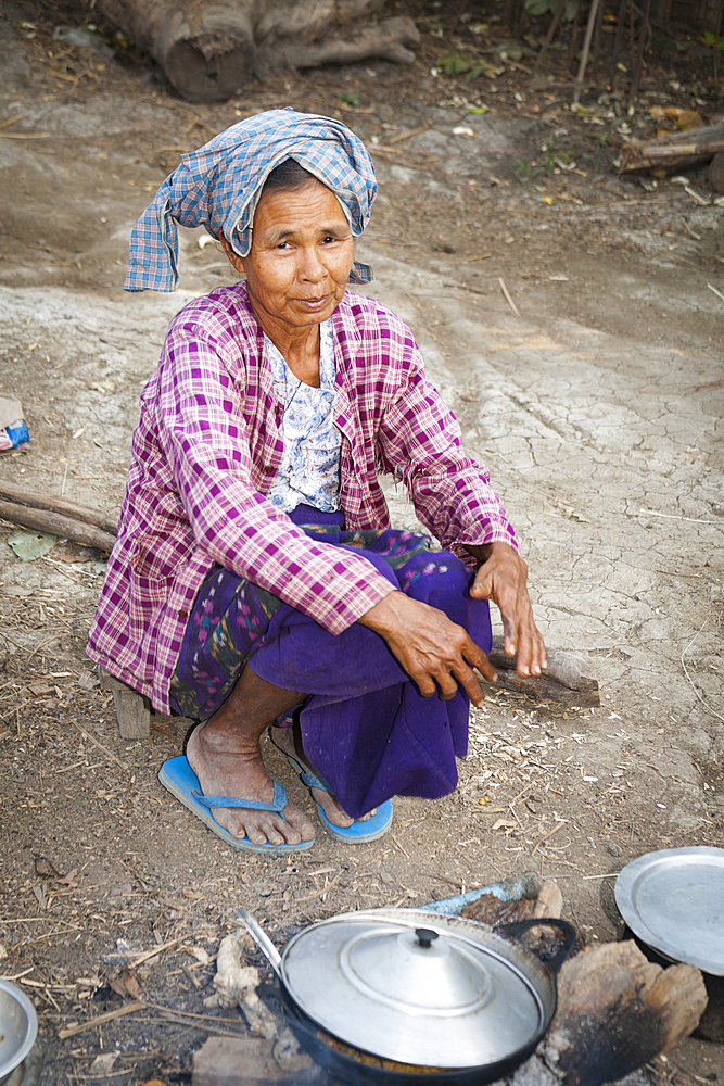 Old woman cooking outside, Yay Kyi village, Mandalay, Myanmar, (Burma)