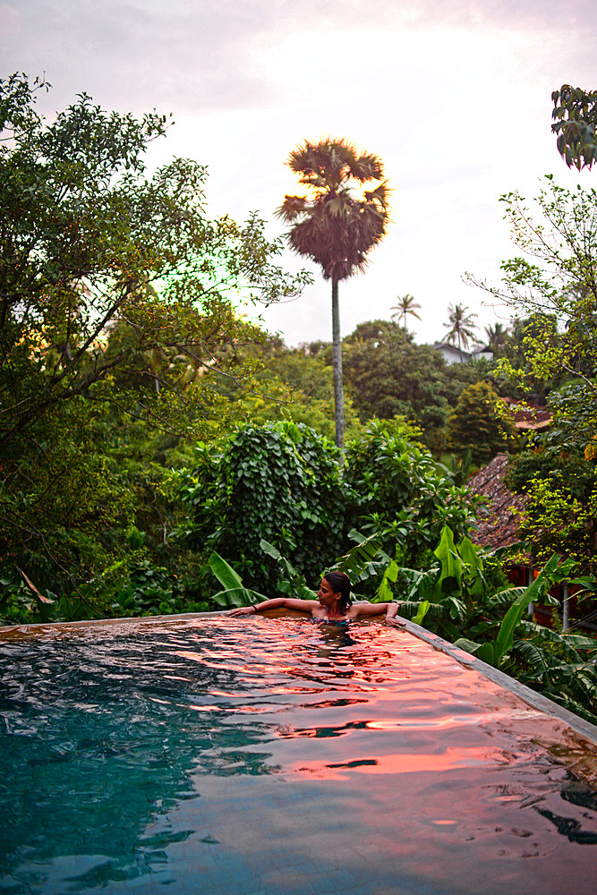 Young attractive woman enjoying a bath in the infinity edge swimming pool at The Dutch House, Galle, Sri Lanka