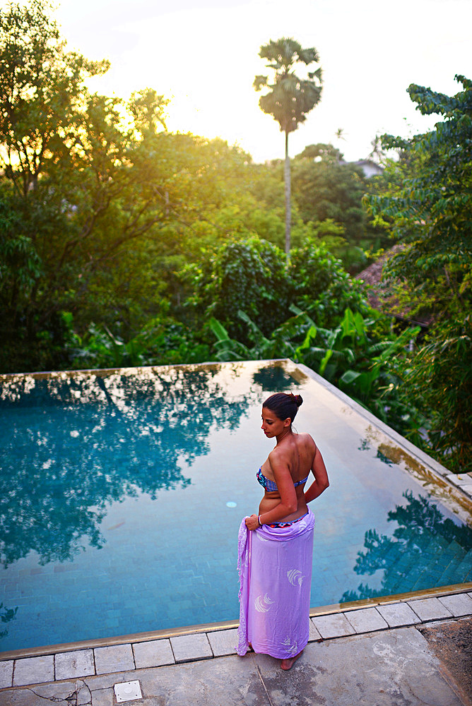 Young attractive woman enters an infinity edge swimming pool at The Dutch House, Galle, Sri Lanka