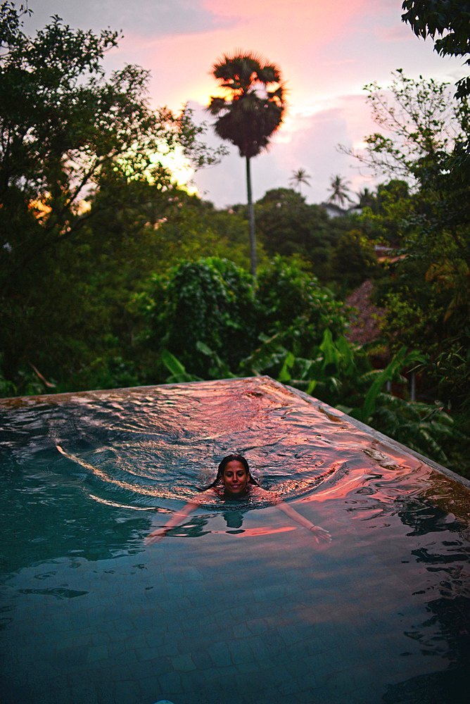 Young attractive woman enjoying a bath in the infinity edge swimming pool at The Dutch House, Galle, Sri Lanka