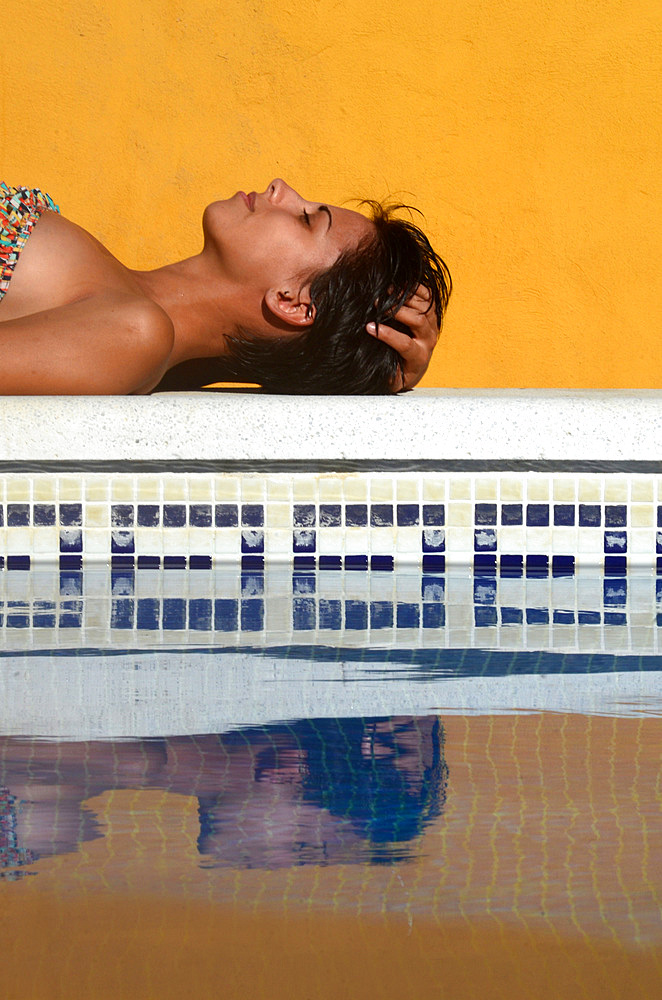 Attractive short haired woman sunbathing by the swimming pool