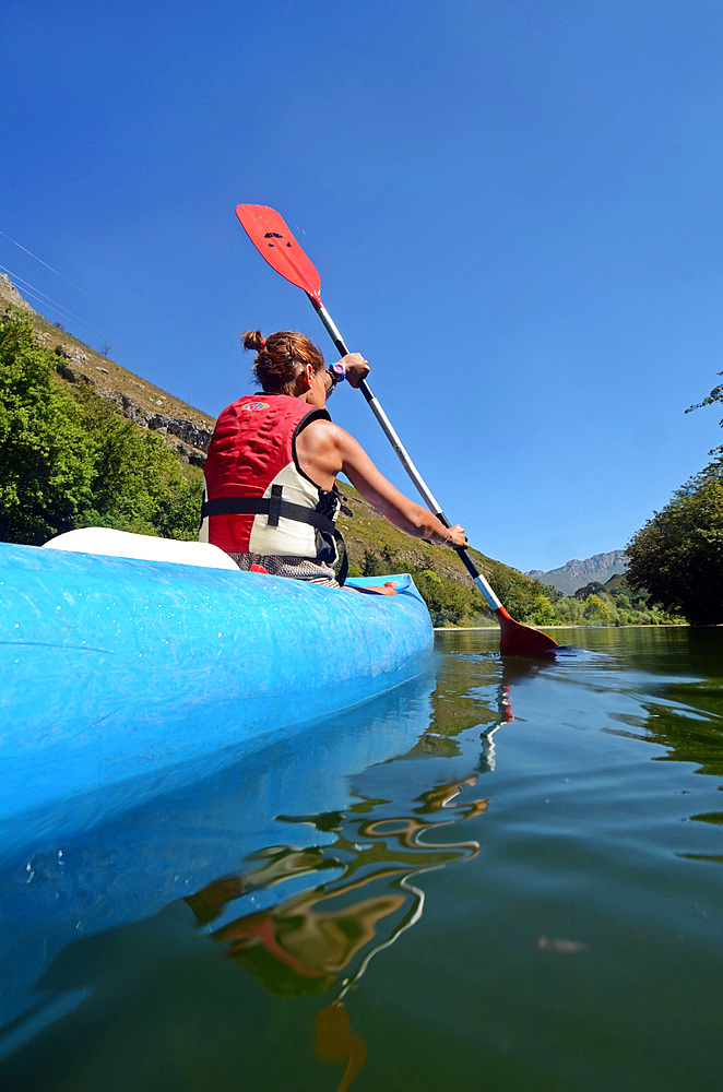 Young woman kayaking in Sella River, Asturias, Spain