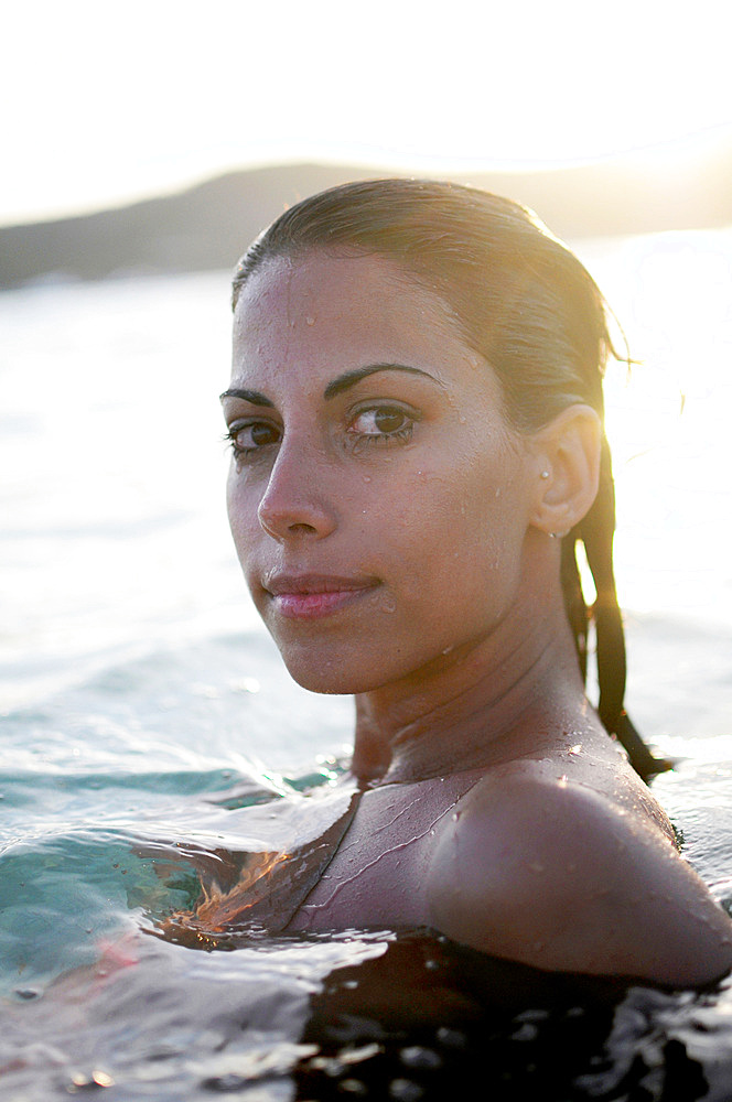 Young attractive woman relaxing at sunset, in the Mediterranean Sea waters