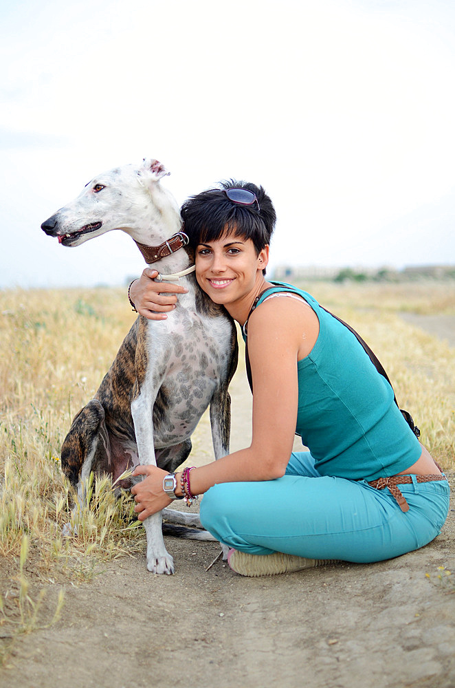 Young attractive woman with her Spanish greyhound in nature