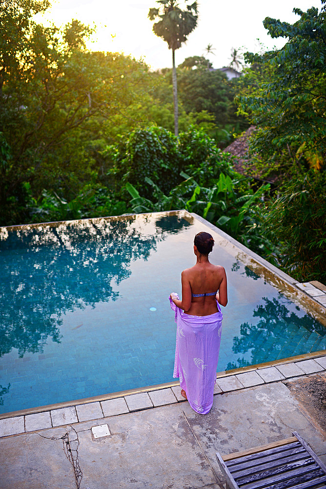 Young attractive woman enters an infinity edge swimming pool at The Dutch House, Galle, Sri Lanka