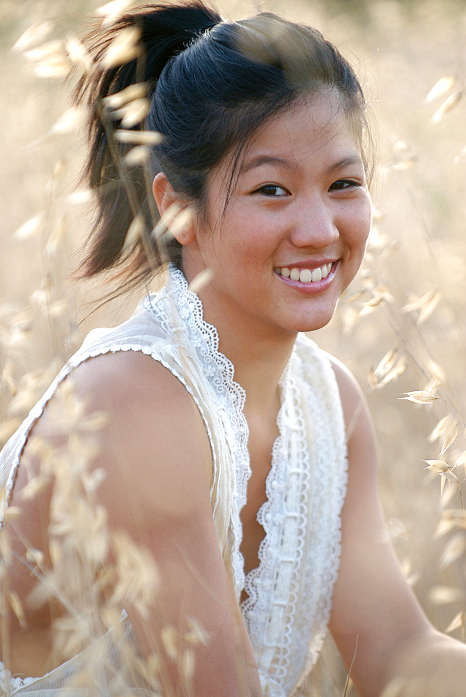 Portrait of a cute young asian woman in a field, at sunset