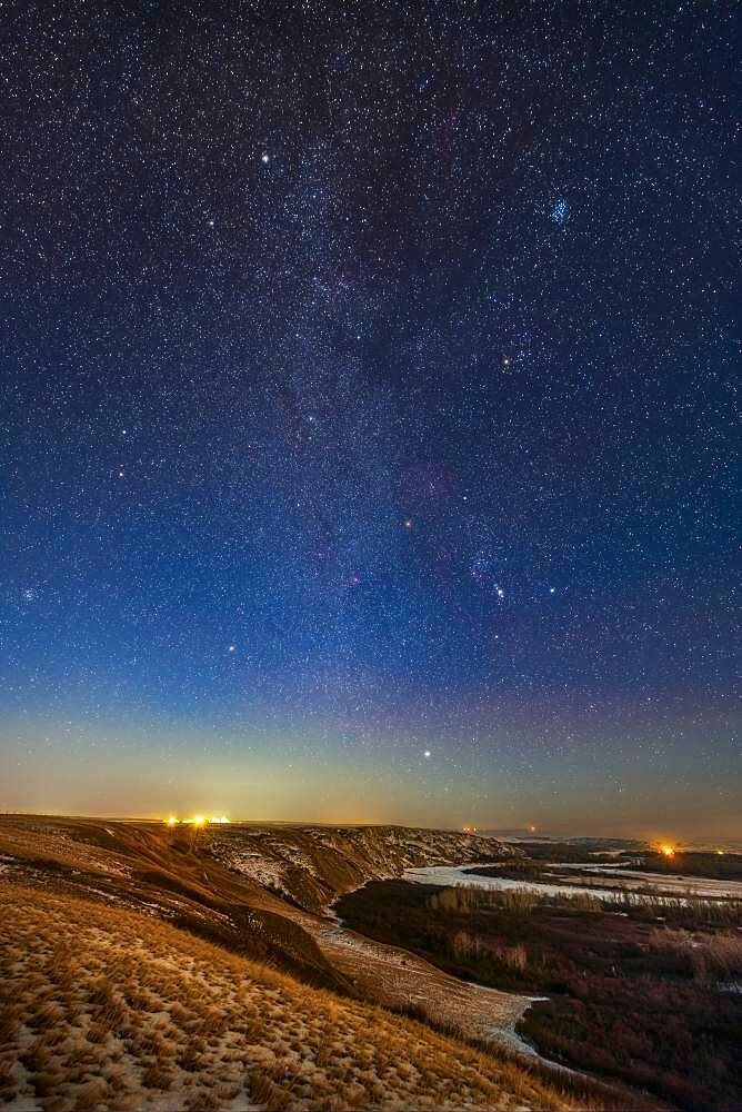 Orion and the winter stars and constellations rising in the light of a first quarter Moon on December 3, 2019. The vertical format sweeps up the Milky Way.