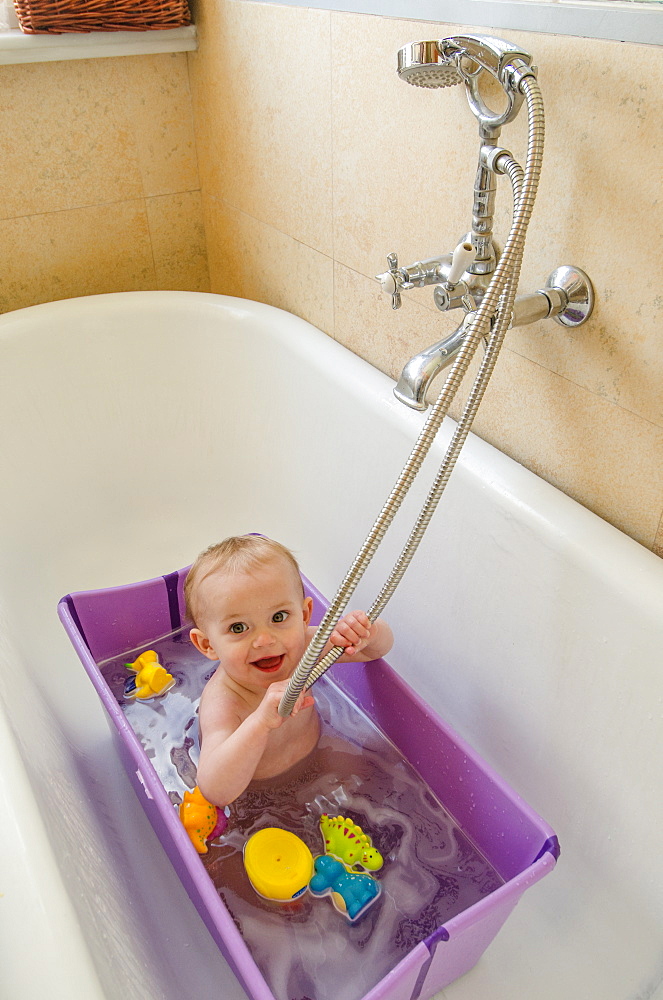 A baby girl (ca. 11 months old) has a bath at home.  (MR: Maude Saez)