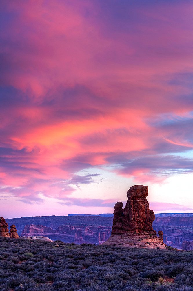 An unnamed Entrada sandstone rock spire with colorul sunset sky in Arches National Park, Moab, Utah.