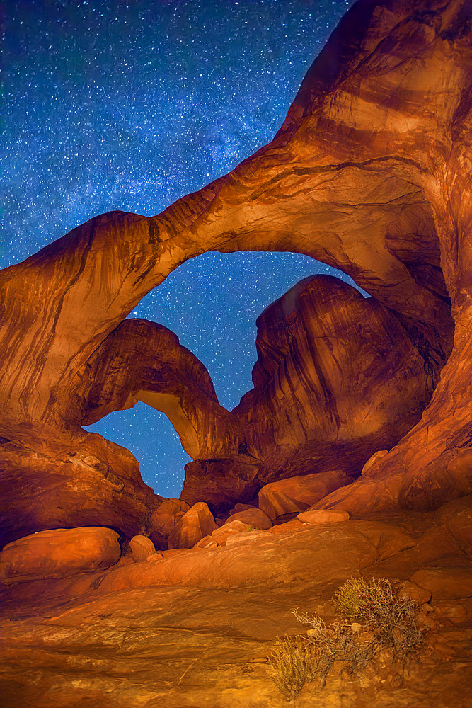 Double Arch at night with the MIlky Way & artificial light painting with a hand-held spotlight. Arches National Park, Moab, Utah.