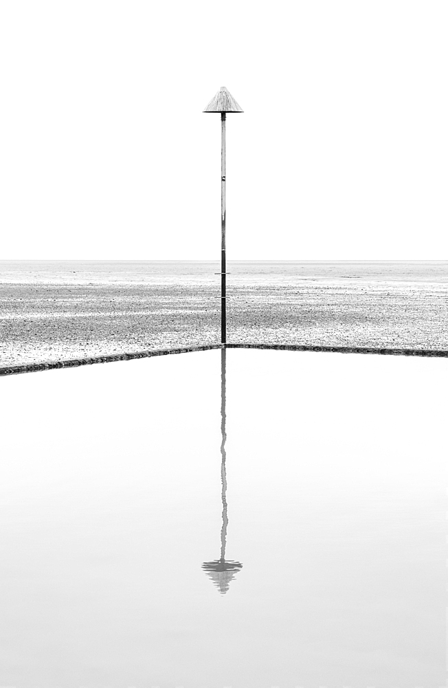 A groyne marker reflected in the tidal pool at low tide, Leigh on Sea, Essex, England, United Kingdom, Europe